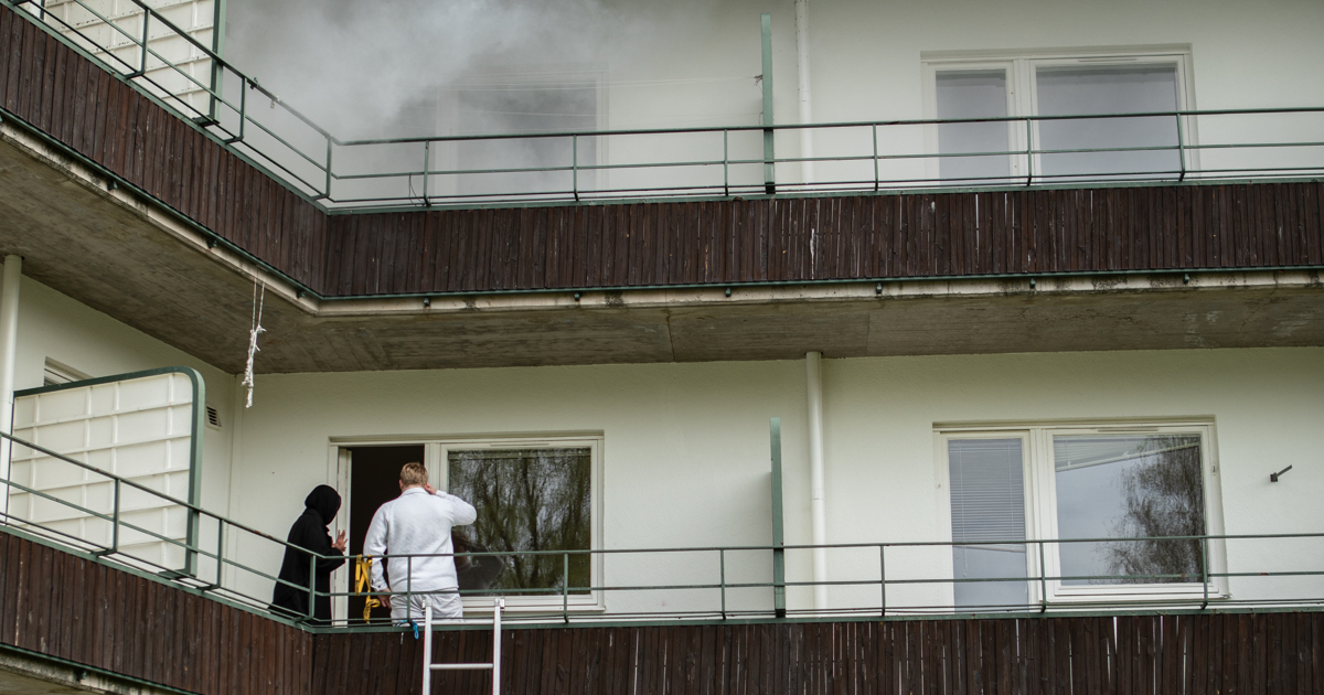 En man står på en stege framför en byggnad.