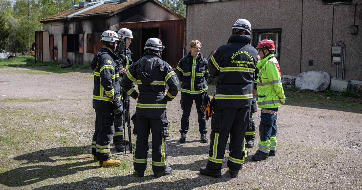 En grupp brandmän står framför en byggnad.