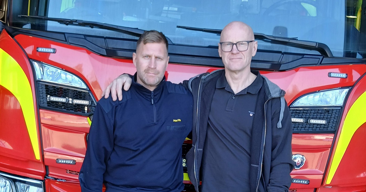 Två män står framför en brandbil.