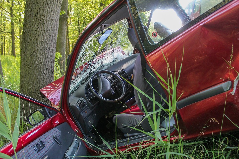 Röd bil som kolliderat med ett träd