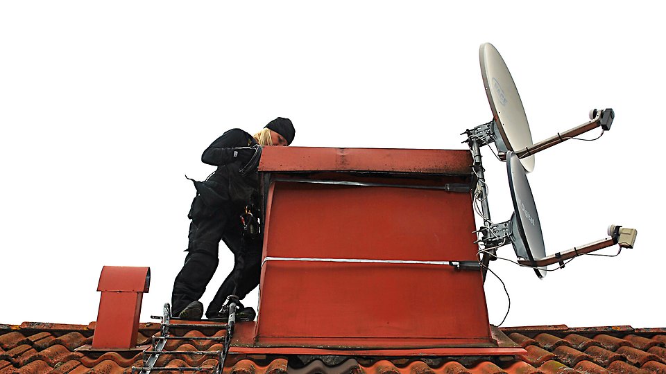 Brandskyddskontrollant som arbetar vid en skorsten på taket